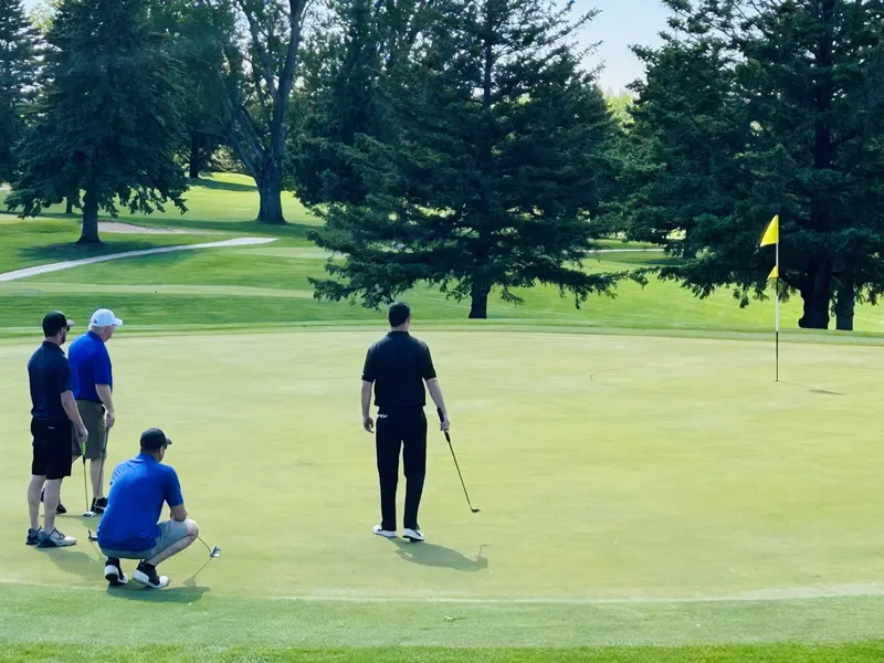 Golfers reading a putt near the flag